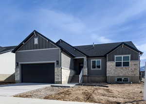 View of front of house featuring driveway, stone siding, a garage, and board and batten siding