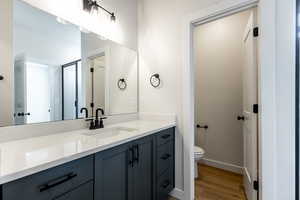 Bathroom with baseboards, vanity, toilet, and wood finished floors