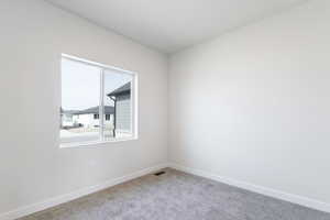 Carpeted empty room featuring visible vents and baseboards