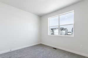 Carpeted spare room with visible vents and baseboards