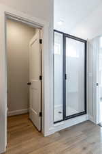 Bathroom featuring a stall shower, baseboards, toilet, and wood finished floors