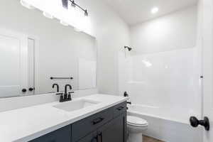 Full bathroom with toilet, shower / tub combination, wood finished floors, and vanity