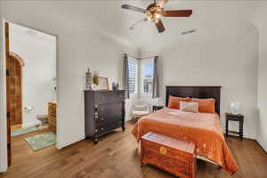 Bedroom with baseboards, visible vents, arched walkways, and wood finished floors