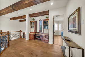 Office featuring built in desk, beamed ceiling, light wood-type flooring, and recessed lighting