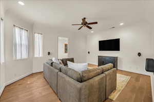 Living area with light wood-type flooring, visible vents, baseboards, and recessed lighting