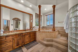 Full bath with a garden tub, decorative columns, a sink, and double vanity