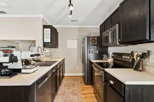 Kitchen with stainless steel appliances, visible vents, a sink, and crown molding