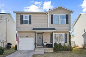 View of front of property featuring a garage, covered porch, driveway, and central AC unit