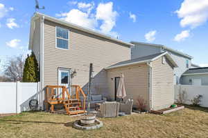 Rear view of house featuring outdoor lounge area, fence, and a lawn