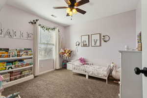 Bedroom with carpet flooring, ceiling fan, visible vents, and baseboards