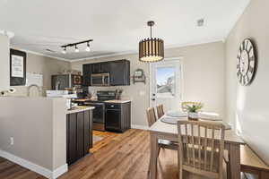 Kitchen featuring stainless steel appliances, ornamental molding, light countertops, and visible vents