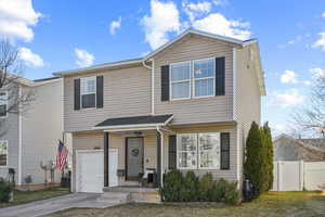 View of front of property featuring driveway, an attached garage, a gate, and fence