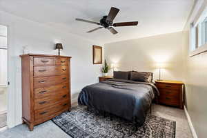 Bedroom with light carpet, a ceiling fan, and baseboards