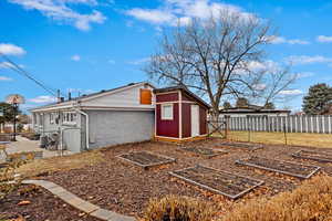 Exterior space with a gate, an outdoor structure, a fenced backyard, and a garden