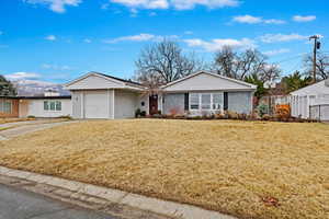 Single story home featuring a garage, concrete driveway, fence, and a front lawn