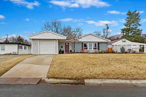 Ranch-style home featuring driveway, a front lawn, an attached garage, and fence