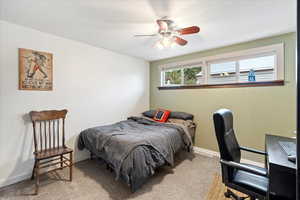 Carpeted bedroom featuring ceiling fan and baseboards