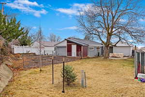 View of front of property with brick siding, a front yard, fence, and a vegetable garden