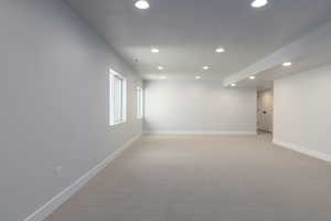 Basement featuring light carpet, baseboards, and recessed lighting