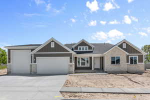 View of front facade with driveway, stone siding, roof with shingles, an attached garage, and board and batten siding