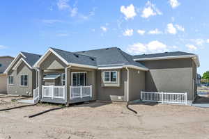 Rear view of house with roof with shingles, a wooden deck, and stucco siding