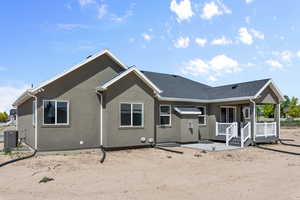 Rear view of property with covered porch, central AC, a shingled roof, and stucco siding