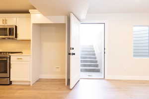 Kitchen featuring appliances with stainless steel finishes, white cabinets, baseboards, and light wood finished floors