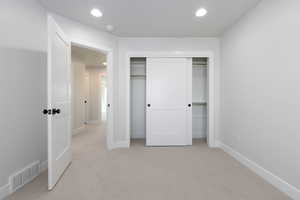 Unfurnished bedroom with light colored carpet, visible vents, baseboards, and recessed lighting