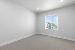 Empty room with light carpet, visible vents, baseboards, and recessed lighting