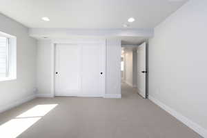 Unfurnished bedroom with a closet, recessed lighting, light colored carpet, and baseboards