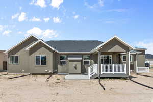 Rear view of property with a porch, roof with shingles, and stucco siding