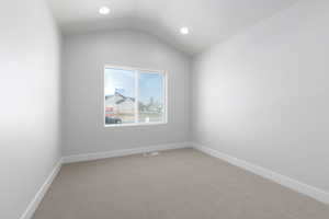 Empty room with lofted ceiling, recessed lighting, light colored carpet, visible vents, and baseboards