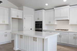 Kitchen featuring appliances with stainless steel finishes, white cabinetry, a kitchen island, and light wood-style flooring