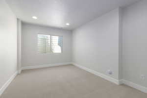 Unfurnished room with light carpet, a textured ceiling, and baseboards