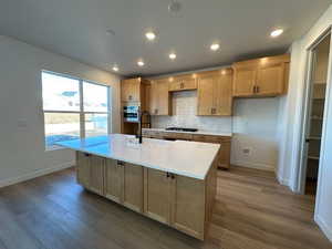 Kitchen with light countertops, backsplash, a sink, gas cooktop, and oven