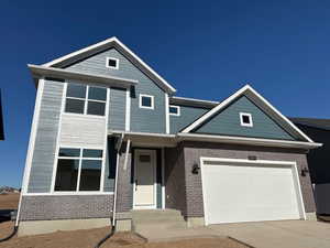 View of front of property featuring a garage, concrete driveway, and brick siding