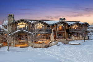 View of front of property featuring a balcony, stone siding, and a chimney
