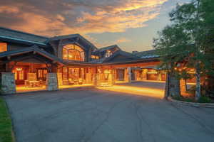 Rear view of property with stone siding, a standing seam roof, asphalt driveway, and a metal roof
