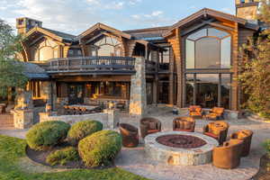 Back of house with an outdoor fire pit, a balcony, a chimney, and a patio