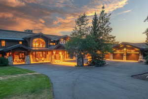 View of front of home featuring a standing seam roof, a metal roof, curved driveway, covered porch, and stone siding