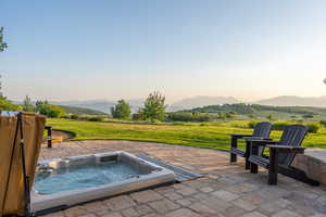 View of patio / terrace with an outdoor hot tub and a mountain view