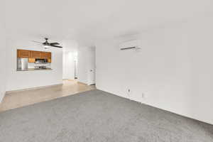 Dining/Living room with a ceiling fan, a wall mounted air conditioner, brand new carpet and pad. Fresh paint.