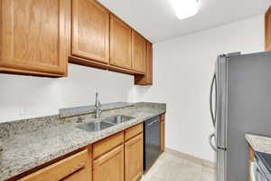 Kitchen featuring stainless steel appliances, travertine tile, and granite countertops.