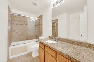 Bath/Shower combo with glass sliding door. Travertine tile and granite countertops.