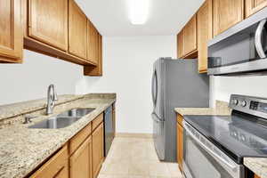 Kitchen featuring stainless steel appliances, travertine tile, and granite countertops.