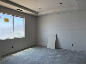Empty room featuring a raised ceiling and concrete floors