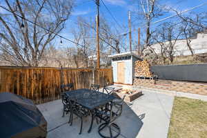 View of patio featuring a storage shed, a fire pit, grilling area, outdoor dining area, and an outdoor structure