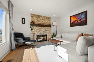 Living room with a stone fireplace, recessed lighting, visible vents, baseboards, and hardwood / wood-style floors