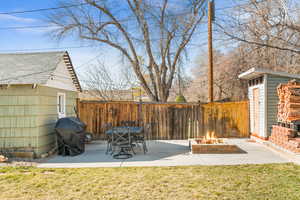 View of yard with a patio, a storage shed, a fenced backyard, an outdoor structure, and a fire pit