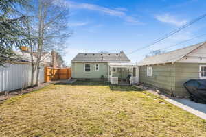 Rear view of property featuring a shingled roof, a patio area, fence, and a lawn